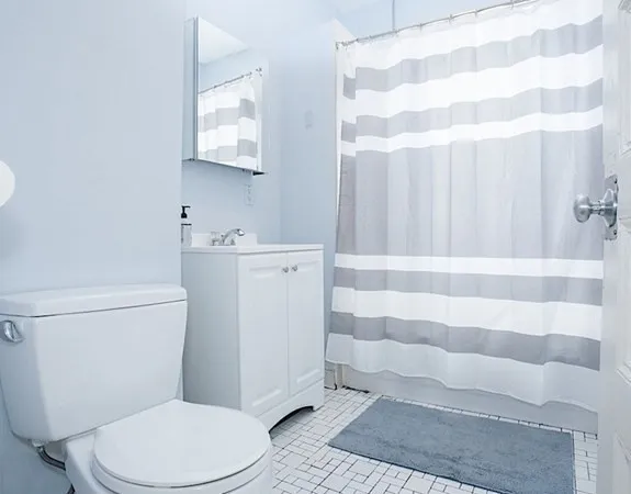 a white toilet sitting next to a white sink and vanity