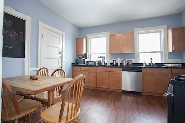 a kitchen with a table chairs a sink dishwasher window and cabinets