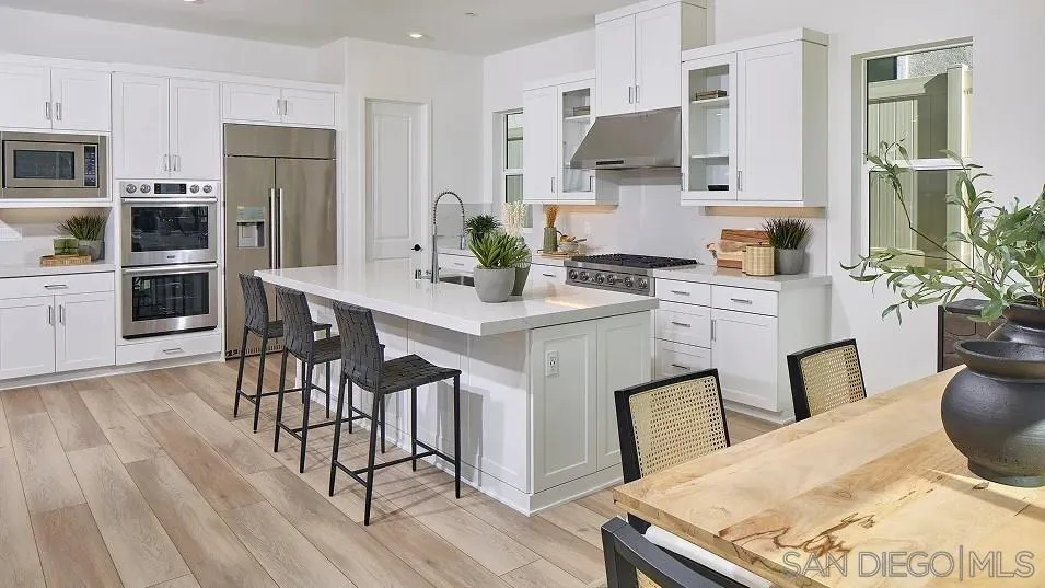 2312 Loker Way Oceanside, CA 92054 - Photo 12 of 20 a kitchen with stainless steel appliances kitchen island granite countertop a refrigerator a stove top oven a sink dishwasher and white cabinets with wooden floor
