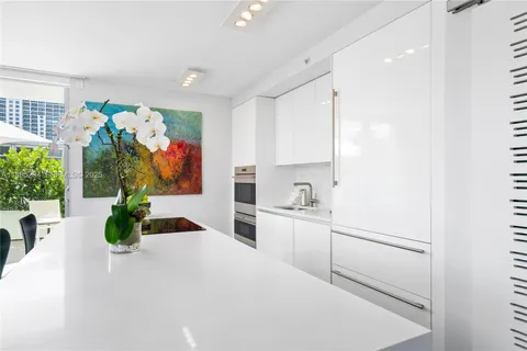 a kitchen with white cabinets and potted plant