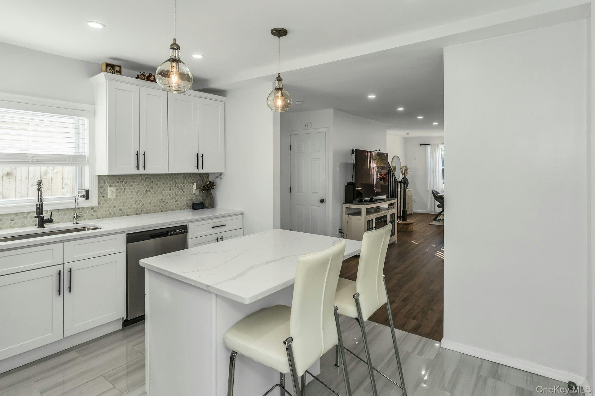 42 13th Street Locust Valley, NY 11560 - Photo 11 of 34 Kitchen with white cabinets, hanging light fixtures, backsplash, light stone countertops, and a center island