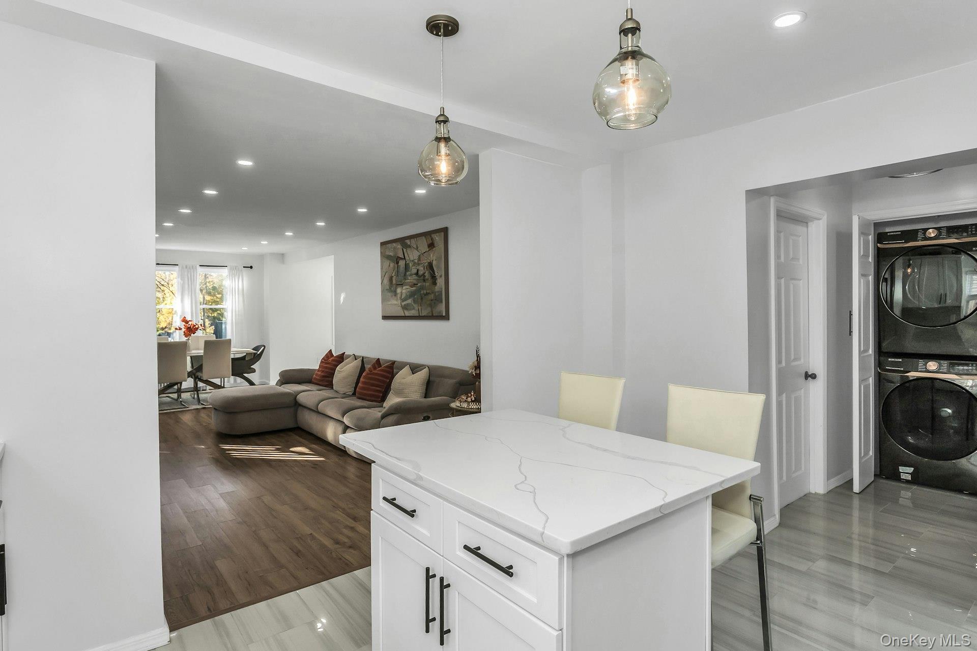 42 13th Street Locust Valley, NY 11560 - Photo 12 of 34 Kitchen with recessed lighting, white cabinets, decorative light fixtures, light stone counters, and stacked washing machine and dryer