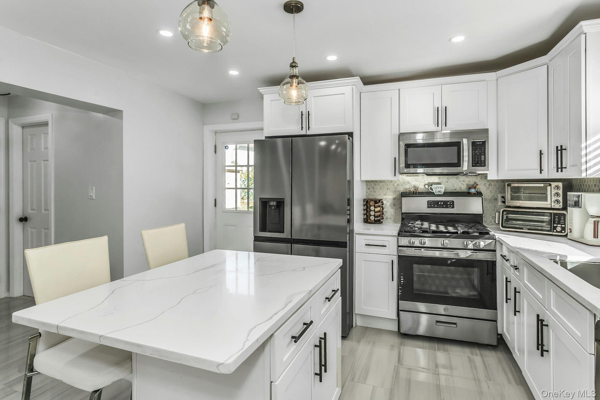 42 13th Street Locust Valley, NY 11560 - Photo 14 of 34 Kitchen with appliances with stainless steel finishes, white cabinets, a breakfast bar, a kitchen island, and recessed lighting