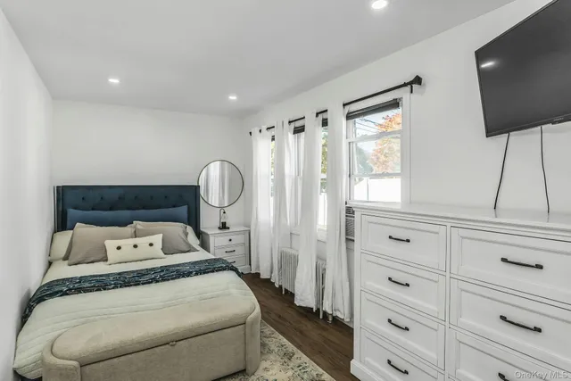 a bedroom with a bed and a flat tv screen on the dresser