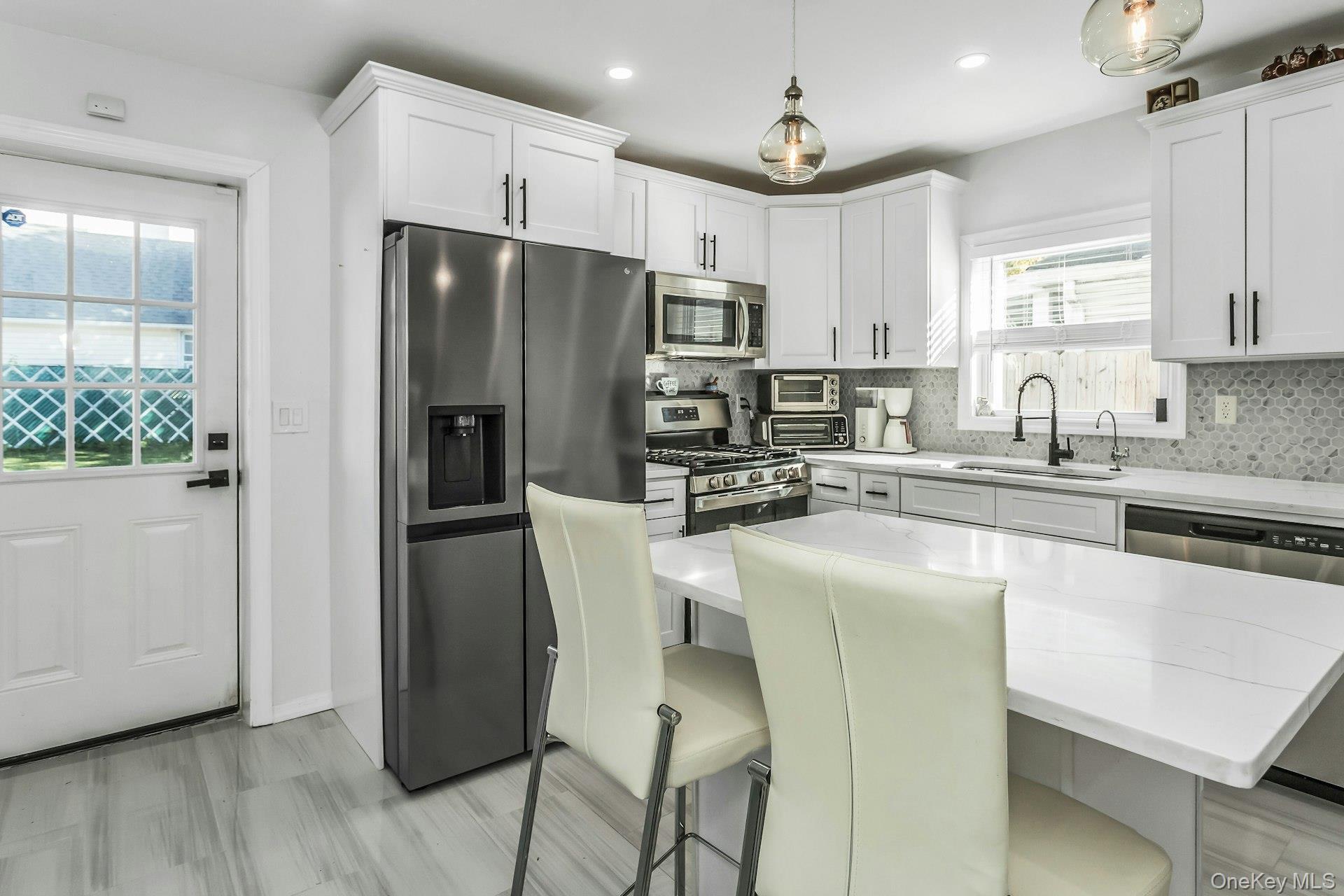 42 13th Street Locust Valley, NY 11560 - Photo 10 of 34 Kitchen with appliances with stainless steel finishes, decorative backsplash, white cabinetry, pendant lighting, and recessed lighting