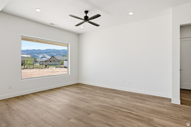 4978 North 75 East Enoch, UT 84721 - Photo 7 of 60 Unfurnished room featuring a mountain view, light wood-style flooring, ceiling fan, and recessed lighting