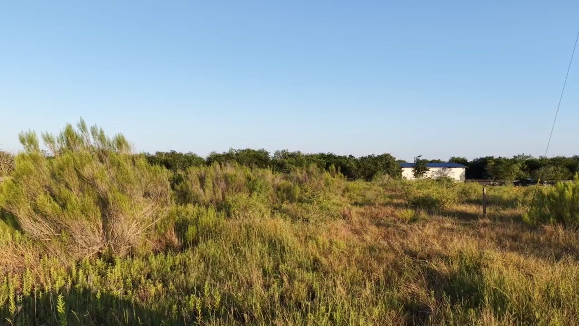 232 East Ridge Lane Kyle, TX 78640 - Photo 19 of 36 A tranquil, undeveloped parcel offers abundant green space and a distant structure under an expansive sky.