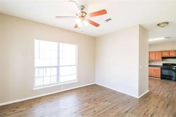 an empty room with wooden floor and a ceiling fan