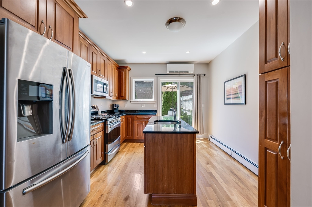 39 Emerson Street Boston, MA 02127 - Photo 7 of 20 a kitchen with stainless steel appliances granite countertop refrigerator a sink dishwasher a stove top oven and a dining table next to a window