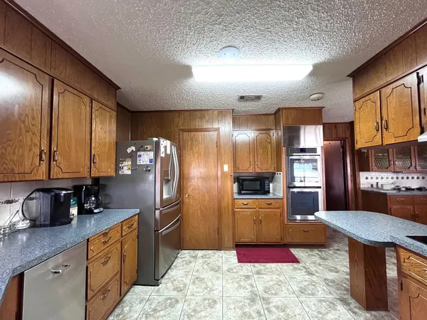 a kitchen with stainless steel appliances kitchen island granite countertop a refrigerator stove and sink
