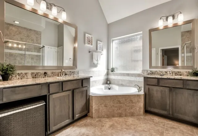a bathroom with a tub double vanity sink and a mirror