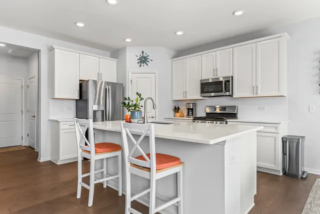 a kitchen with stainless steel appliances a refrigerator stove microwave and white cabinets