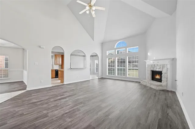 an empty room with wooden floor fireplace and windows