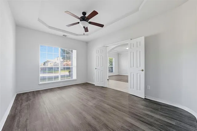 an empty room with wooden floor and windows