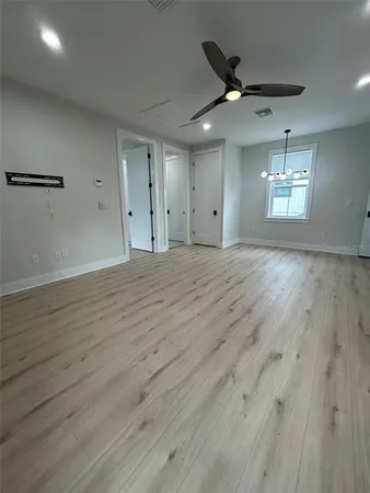 an empty room with wooden floor ceiling fan and windows
