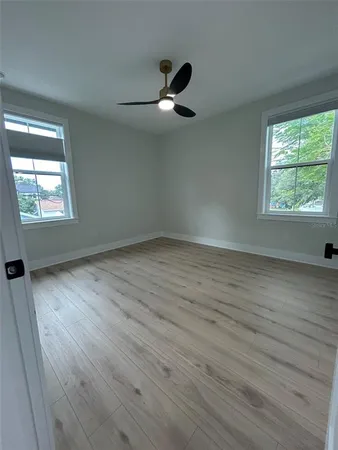 an empty room with wooden floor and windows