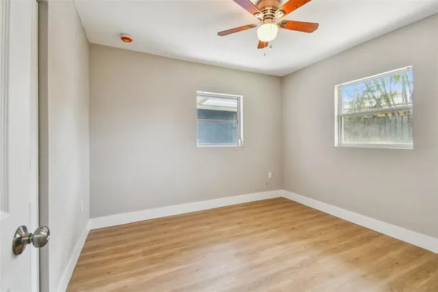 an empty room with a window and a ceiling fan