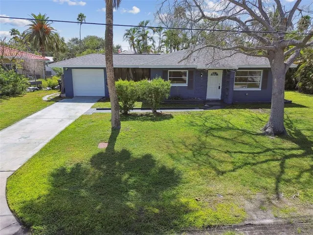 a view of a brick house with a yard potted plants and large tree