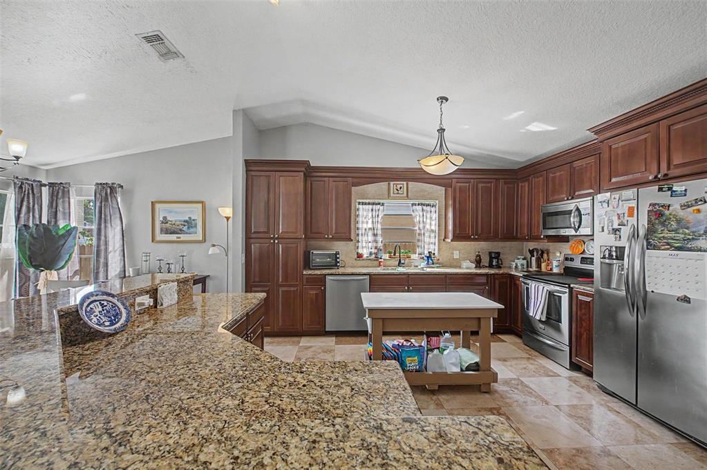 1632 Pintail Court Lutz, FL 33549 - Photo 14 of 34 a large kitchen with stainless steel appliances granite countertop a sink refrigerator dining table and chairs