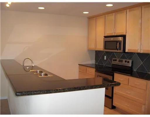 a kitchen with kitchen island granite countertop a sink a stove and microwave