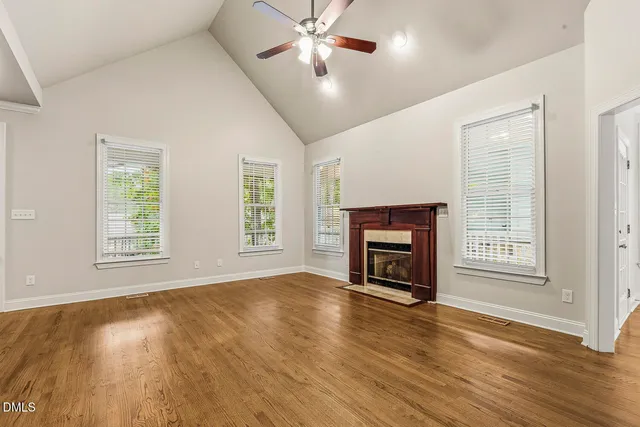a view of an empty room with window fireplace and wooden floor