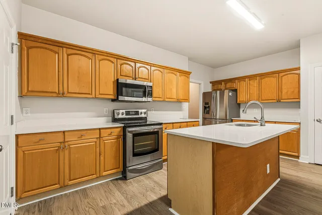 a kitchen with stainless steel appliances a sink a stove and a refrigerator with wooden floor