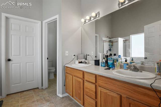 8036 Ferguson Road Peyton, CO 80831 - Photo 14 of 29 Bathroom with dual vanity, tile flooring, and toilet