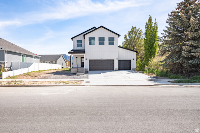 2535 West Santa Fe Drive Mapleton, UT 84664 - Photo 4 of 26 Modern farmhouse exterior featuring white vertical siding, black-framed windows, a covered entry, and two dark garage doors