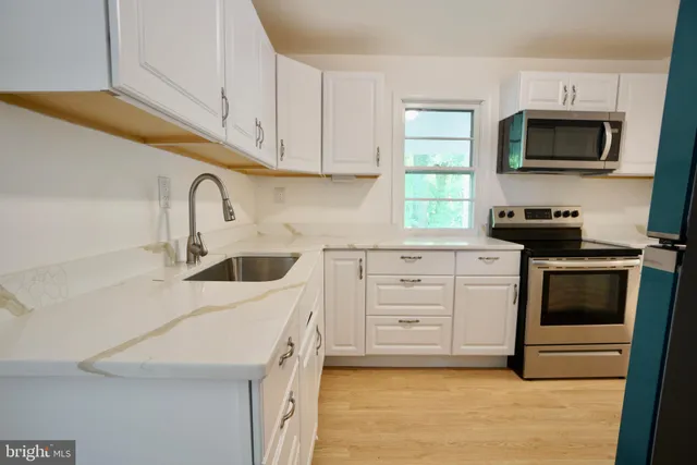 a kitchen with white cabinets stainless steel appliances and a sink