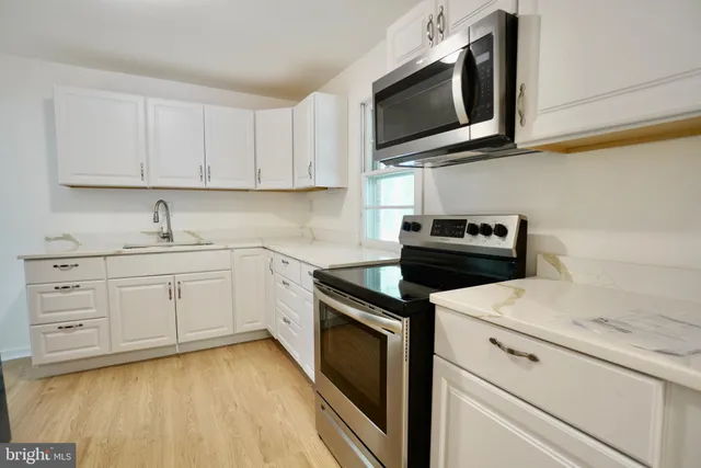 a kitchen with white cabinets stainless steel appliances and sink