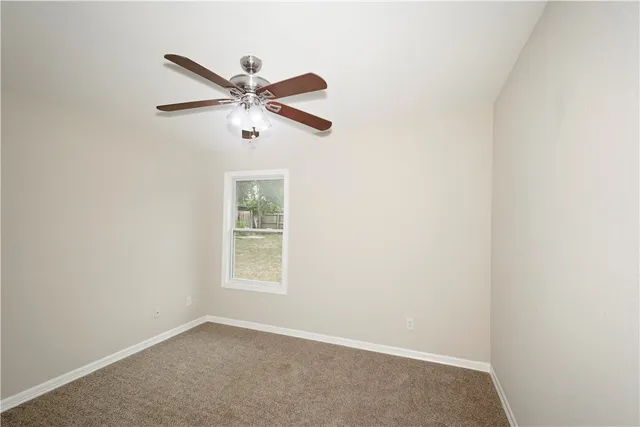 an empty room with a window and a ceiling fan