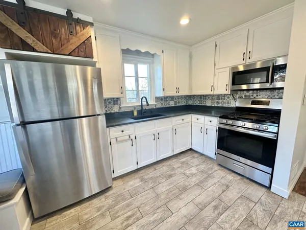 a kitchen with stainless steel appliances granite countertop a refrigerator a stove a sink and a microwave