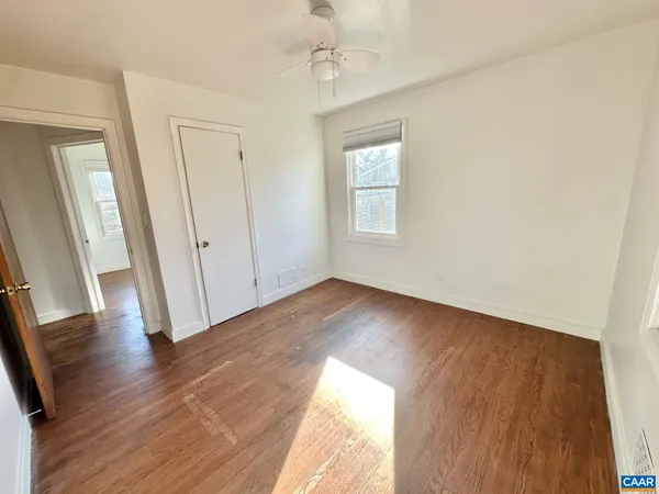 an empty room with wooden floor and windows