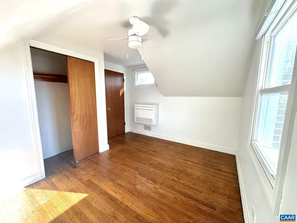 a view of empty room with wooden floor and fan