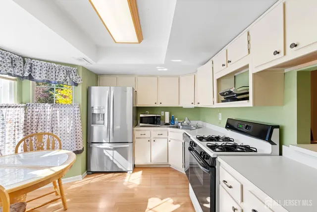 a kitchen with stainless steel appliances granite countertop a stove a sink dishwasher a refrigerator white cabinets and wooden floor