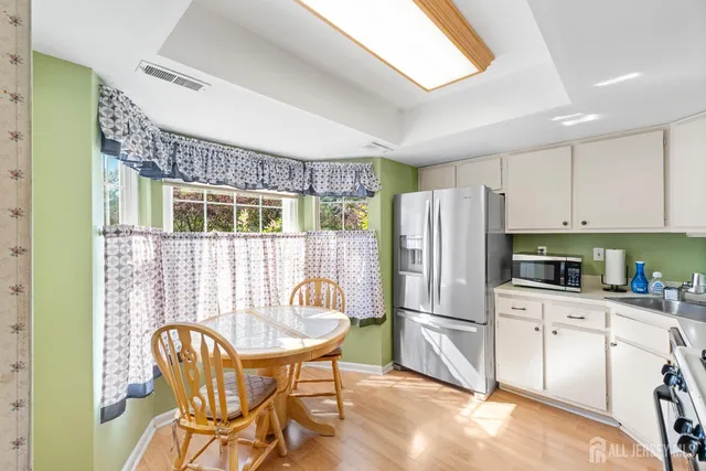 a kitchen with stainless steel appliances granite countertop a dining table chairs a refrigerator and cabinets