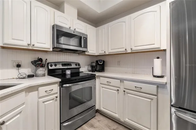 a kitchen with white cabinets and white appliances