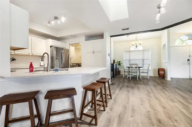 a kitchen with stainless steel appliances a dining table chairs and wooden floor