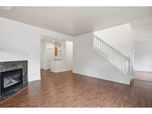a view of an empty room with wooden floor fireplace and a window