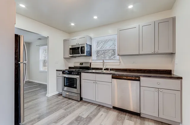 a kitchen with granite countertop white cabinets and stainless steel appliances