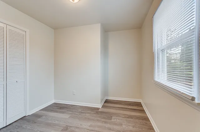 a view of an empty room with wooden floor and a window