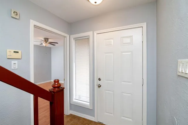 a view of a livingroom with wooden floor a fireplace a ceiling fan and windows
