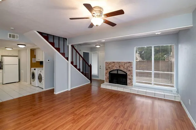 an empty room with wooden floor and a kitchen
