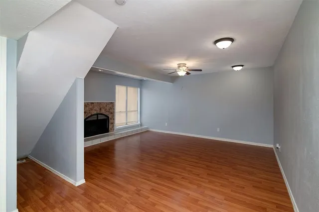 an empty room with wooden floor and a ceiling fan