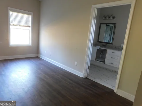 an empty room with wooden floor cabinet and windows