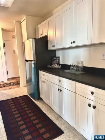 a kitchen with granite countertop a refrigerator sink and cabinets