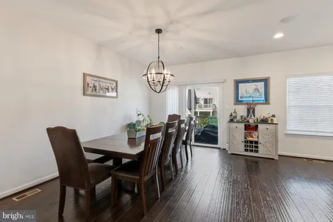 a dining room with wooden floor a chandelier a wooden table and chairs