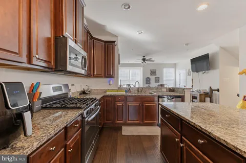 a kitchen with stainless steel appliances granite countertop a stove top oven a sink dishwasher and cabinets with wooden floor
