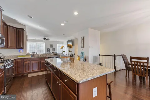 a kitchen with granite countertop kitchen island stainless steel appliances a table chairs sink and stove