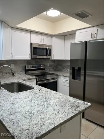 a kitchen with stainless steel appliances granite countertop a sink a microwave a refrigerator and counter space